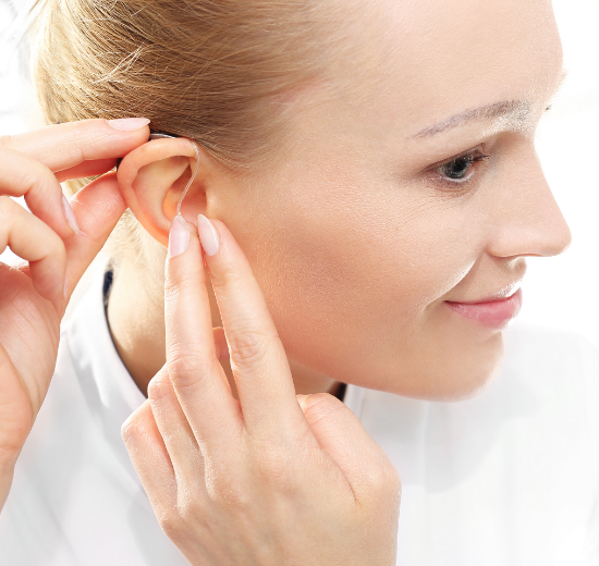 Frau beim Einsetzen eines Hörgeräts mit externem Hörer.